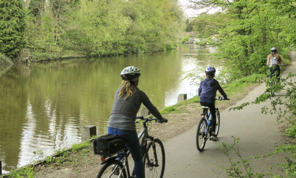Photo of cyclists riding along riverbank