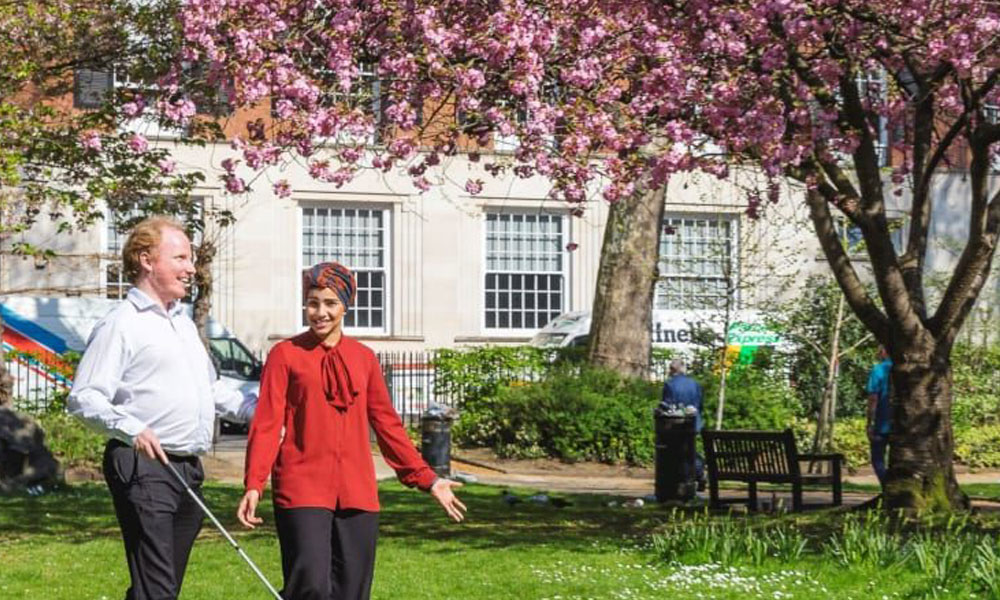 Photo of visually impaired individual walking in park