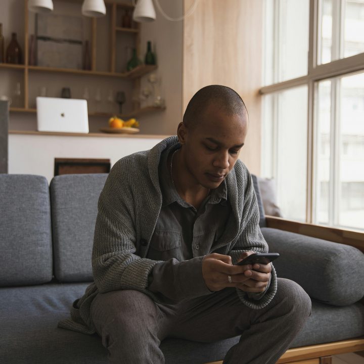 Man Using Mobile Phone On Sofa At Home Aspect Ratio 720 720