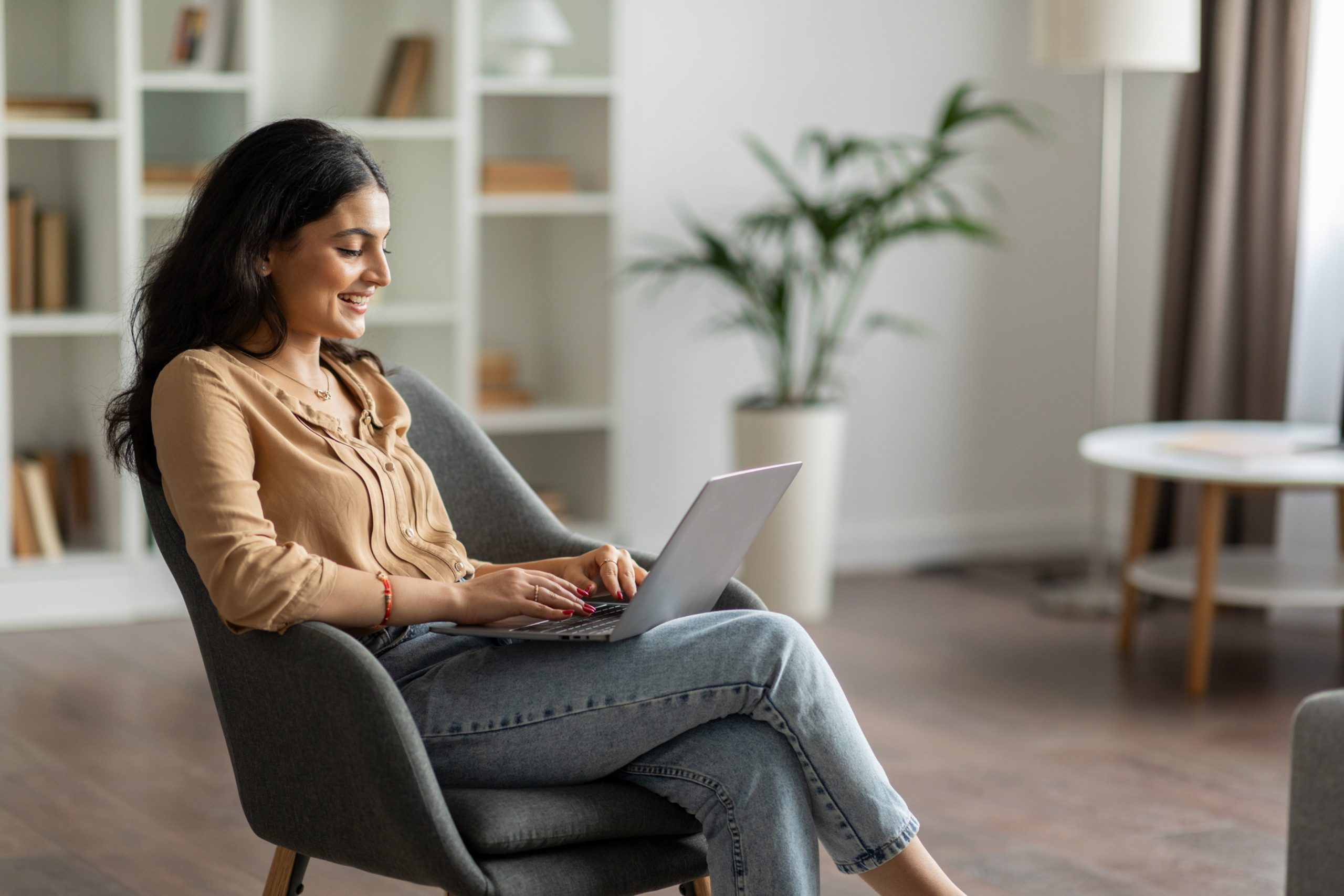 Woman Sitting On Chair Checking Emails On Laptop