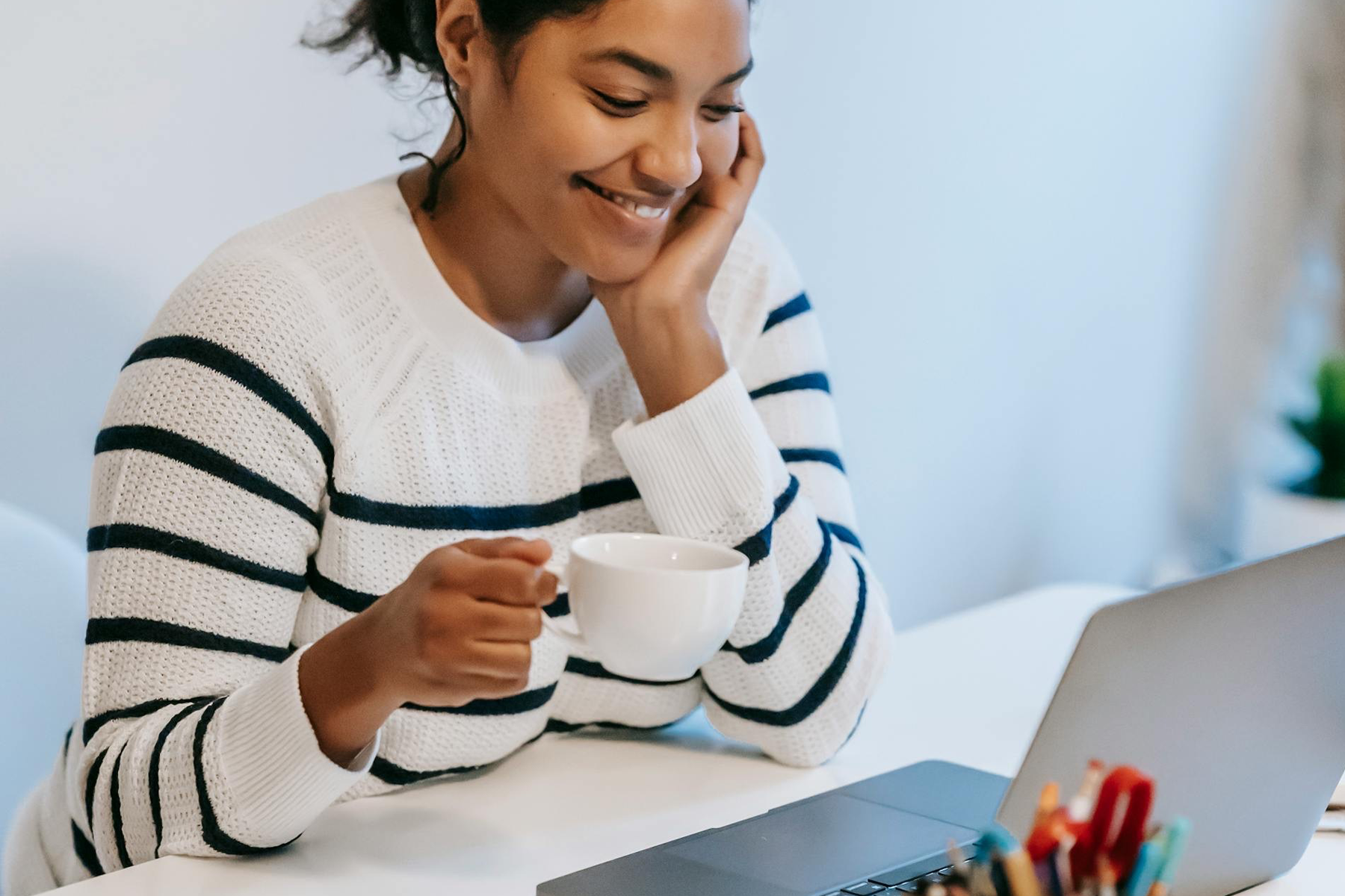 Young Woman Drinking Coffee And Using A Laptop