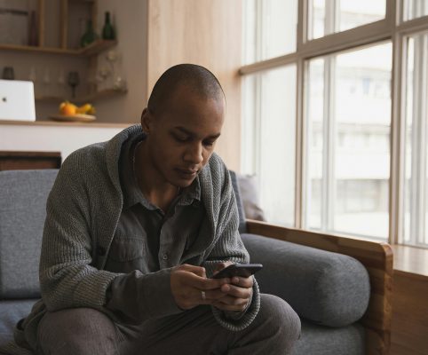 Man Using Mobile Phone On Sofa At Home Aspect Ratio 482 400