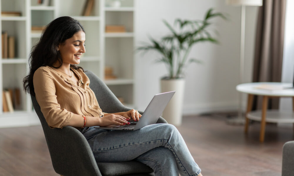 Woman Sitting On Chair Checking Emails On Laptop Scaled Aspect Ratio 1000 600